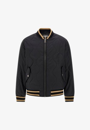 Black quilted bomber jacket featuring a zip front, side pockets, and striped ribbed cuffs and hem in black and gold accents.