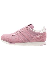 Rosa sneaker med en blandning av texturerade material, inklusive mocka och konstgjord ormskinn, med vit sula och varumärke på sidan.