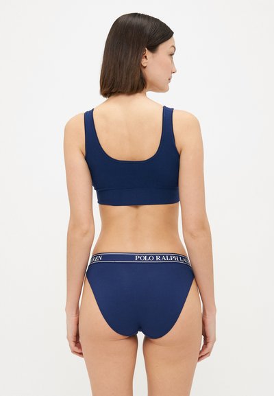 Navy cotton bra with wide straps and low back. Matching navy underwear features a white branded waistband and a high-cut leg design.