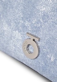 Denim tas in lichtblauw met een gestructureerde afwerking, met een zilveren metalen logoaccent. Het ontwerp bevat een opvallende cirkelvormige uitsnede.