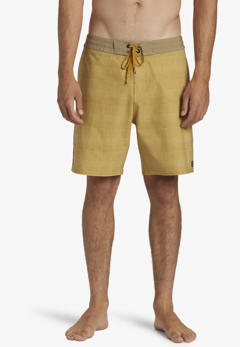 Shorts de bain à carreaux jaunes en tissu doux, avec une taille élastique et un système de fermeture par cordon. Comprend des poches latérales et un design léger.