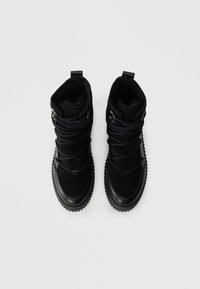 Fekete boka csizmák texturált felső anyaggal, vastag fűzőkkel, cipzár díszítéssel és strapabíró talppal, puha béléssel az insuláció érdekében.