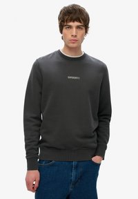 Mørkegrå crewneck sweatshirt lavet af blød bomuldsblanding, med ribbede manchetter og kant, samt et subtilt hvidt "SUPERDRY" logo på brystet.