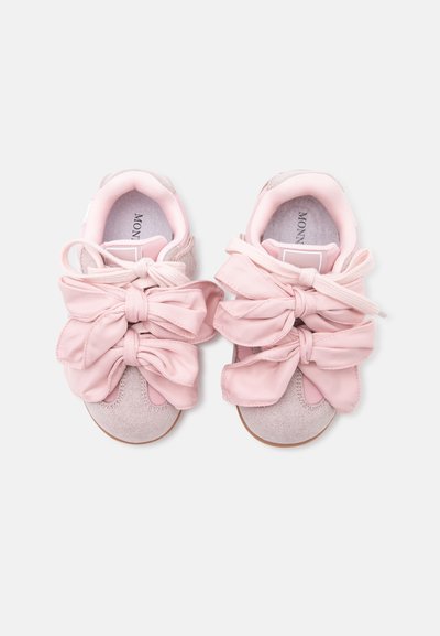 Paire de baskets rose clair avec de grands nœuds en tissu noués sur le dessus, en daim doux avec intérieur rembourré.
