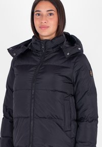 Giubbotto puffer nero con zip frontale, cappuccio e tessuto testurizzato. Presenta sezioni cucite e una tasca laterale per praticità.
