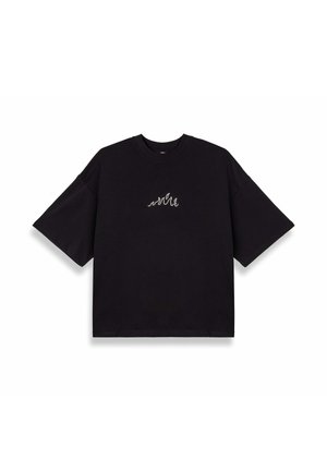 T-shirt nera oversize in cotone con maniche corte. Presenta un piccolo design a onda bianco ricamato sul petto. Taglio semplice e moderno.