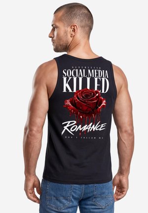 Mann trägt ein schwarzes Tanktop mit einer roten blutenden Rose und dem Text "Social media killed romance" auf dem Rücken.