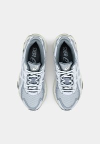 Zapatillas de running de malla gris con acentos en gris claro, que cuentan con puntera redonda, talón reforzado y un sistema de cordones tradicional.