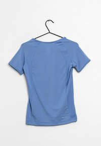 Vaaleansininen urheilupaita lyhyillä hihoilla, sileä pinta ja pyöreä pääntie. Ominaisuuksiin kuuluvat kaarevat saumat ja logo helman lähellä.