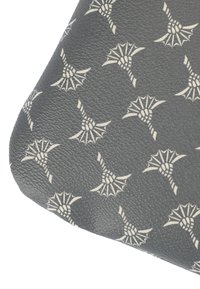 Primo piano di materiale grigio scuro texturizzato con un motivo ripetuto di nodi intrecciati bianchi e forme a ala.