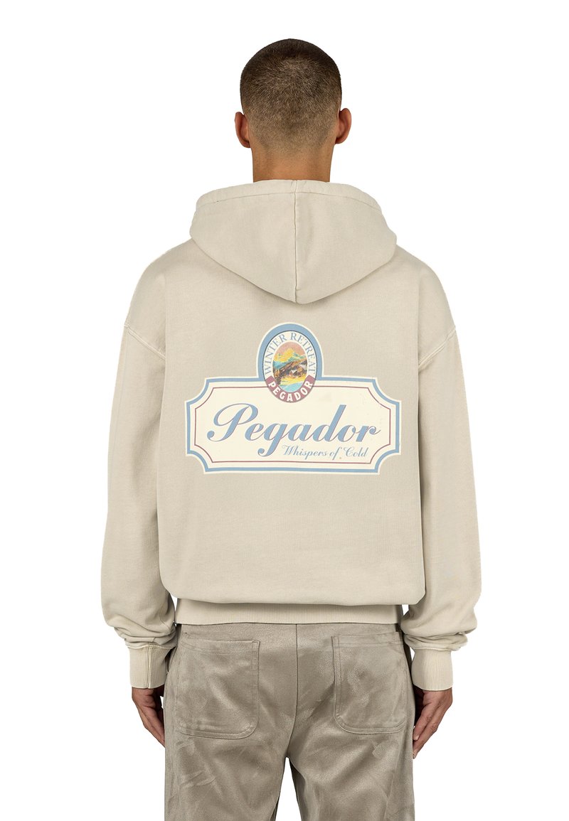 Felpa beige con cappuccio e cordino, caratterizzata da una grande grafica stampata sul retro che include testo e un design paesaggistico.