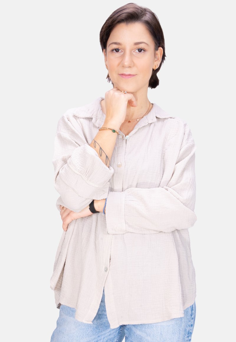 Light grey, relaxed-fit button-up shirt with a textured fabric. Paired with blue jeans, showcasing casual style.