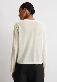 Cremefarbener Pullover mit langen Ärmeln, weicher Textur, runder Halslinie und lockerer Passform, mit sichtbarer Naht am Rücken.