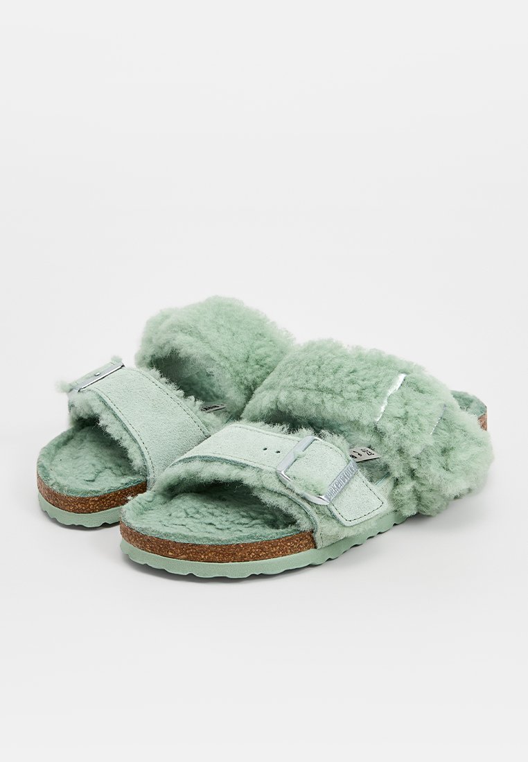 Mintgrüne, mit Fell gefütterte Sandalen mit zwei verstellbaren Riemen, Korkfußbett und strukturierter Gummisohle. Weiche Textur und gemütliches Design.