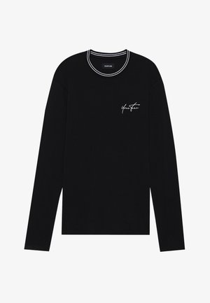 Hosszú ujjú fekete póló, kerek nyakkivágással, fehér csíkos gallérral és kis fehér hímzett szöveggel a mellkasán.