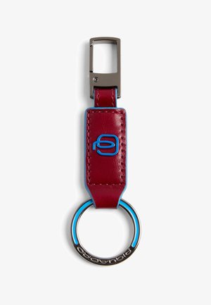 Rode leren sleutelhanger met blauwe stiksels en logo, metalen ring met blauwe accenten en rechthoekige zilveren clip.
