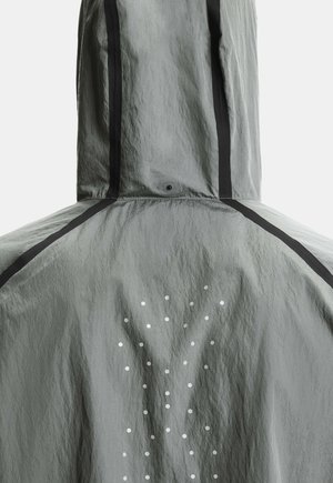 Veste grise à capuche avec des rayures verticales noires et un motif de petits points blancs formant un Y dans le dos.