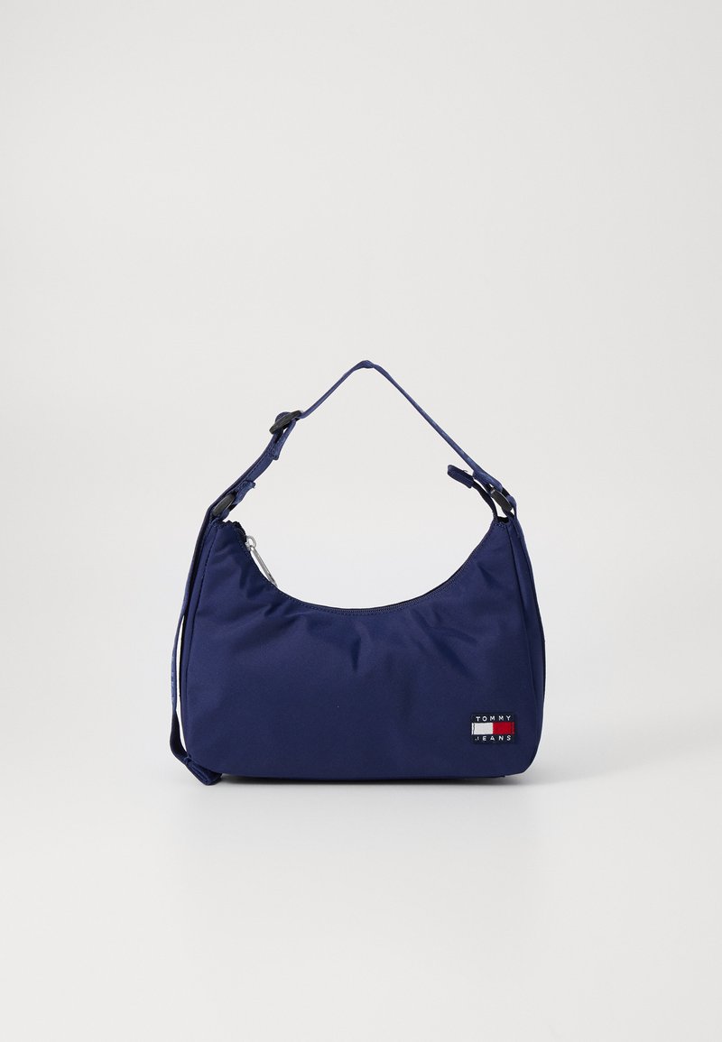 Sac à épaule Tommy Jeans bleu marine avec sangle ajustable et fermeture éclair, arborant un petit patch logo à l'avant.