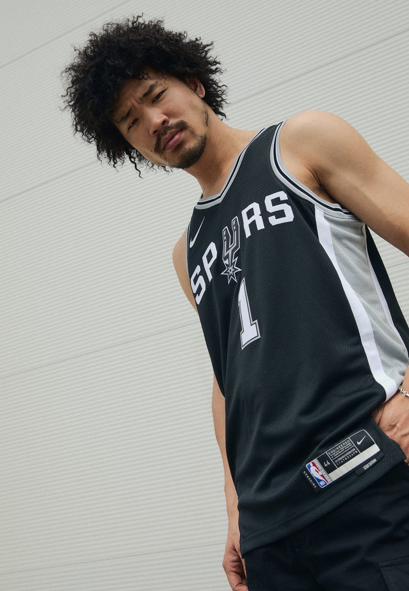 Juodas krepšinio marškinėliai su baltais ir pilkais akcentais, su užrašu "SPURS", numeriu "1" ir Nike logotipu. Tekstūruota medžiaga su šoniniais etiketės detalėmis.