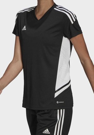 Person wearing black Adidas sportswear with white stripes on shoulders and sides, including a short-sleeve shirt and matching shorts.