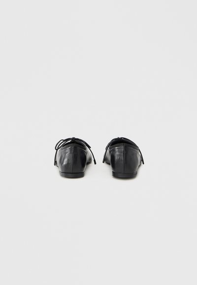 Μαύρα δερμάτινα παπούτσια με επίπεδη σόλα και στρογγυλεμένη μύτη, με μικρό τακούνι και φιόγκο στο πίσω μέρος. Λείο υλικό με λιτό σχεδιασμό.