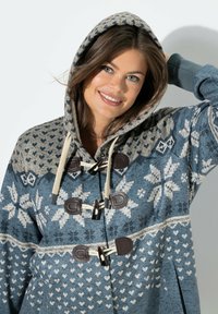 Blå mönstrad hooded jacka med snöflingor och hjärtmotiv. Har togglestygn, beige detaljer och en avslappnad passform. Mjuk textur.