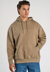 Sudadera con capucha beige hecha de una mezcla de algodón, con un bolsillo frontal y puños de canalé. Logo impreso en blanco en el pecho.