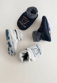 Bomullsbabystövlar i grått och marinblått. Funktioner inkluderar broderade mönster, randiga muddar och texturerade sålar med tassavtryck.