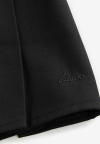 Zwarte stoffen schoen met een gladde textuur, strakke lijnen en een subtiele geborduurde "Clarks"-logo dichtbij de rand.
