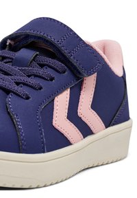 Fioletowe trampki z różowymi akcentami, zapięcie na rzep, teksturowana powierzchnia, wyściełany kołnierz oraz biała gumowa podeszwa z bieżnikiem.