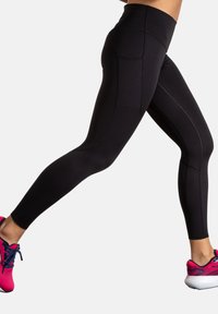 Leggings neri a vita alta realizzati in tessuto elasticizzato, dotati di una tasca laterale e cuciture piatte per garantire comfort durante il movimento.