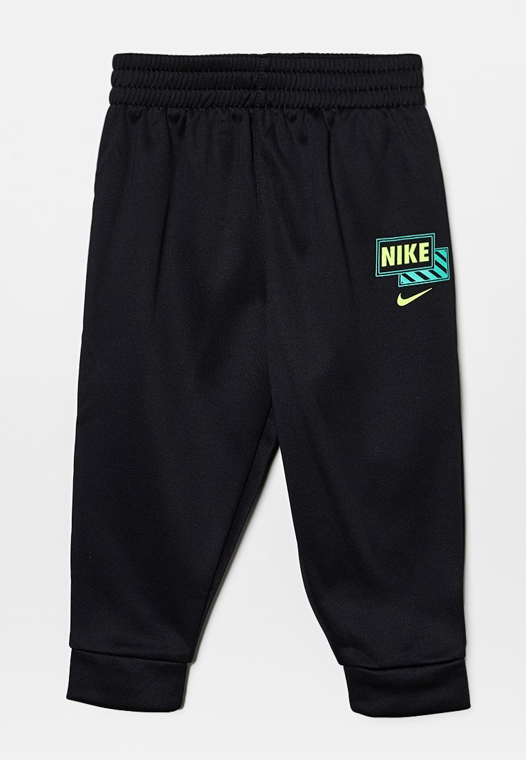 Pantaloni per bambini neri Nike con elastico in vita e logo verde neon sulla coscia sinistra, con un design grafico dietro il nome del marchio.