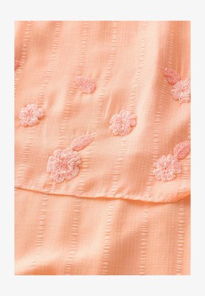 Perzikkleurige stof met verticale strepen heeft geborduurde lichtroze bloemen en bladeren. De textuur is glad met een subtiele glans.