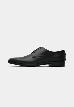 Schwarze Lederschuhe mit glatter Oberfläche, runder Zehenform, niedrigem Absatz und Schnürdesign. Minimalistische Akzente sorgen für ein elegantes Erscheinungsbild.