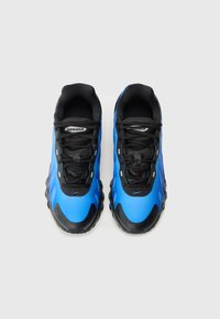 Des chaussures de sport bleu et noir avec une tige lisse et brillante, une surface texturée, des lacets noirs et un coussin d'air le long d'une semelle en caoutchouc épaisse.