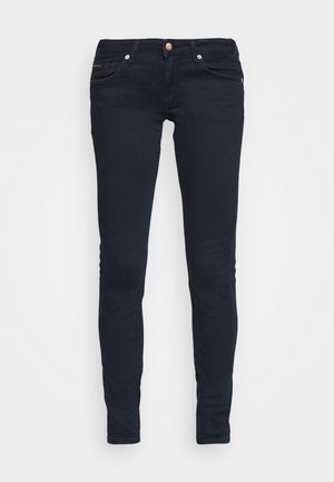 Jeans skinny em denim azul escuro, com cintura media, dois bolsos frontais e detalhes metálicos na cintura e nos bolsos.