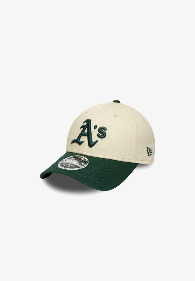 Beige baseball cap with dark green visor, featuring a raised, embroidered "A's" logo on the front. New Era logo on the side. Textured fabric.