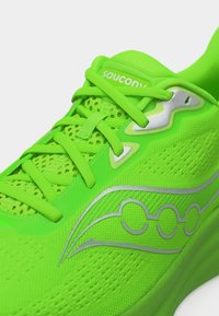 Φωτεινό πράσινο αθλητικό παπούτσι Saucony με επάνω μέρος από δίχτυ, πράσινα κορδόνια και ασημένιο λογότυπο στην πλευρά.