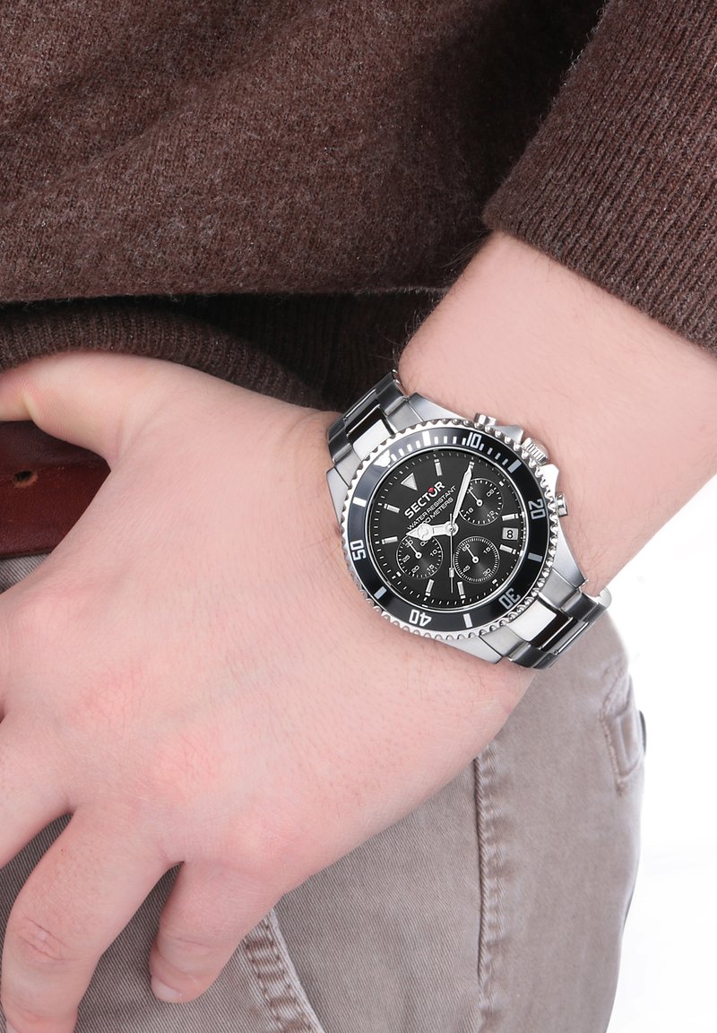 Orologio cronografo nero con cinturino in acciaio inossidabile argentato, dotato di cassa rotonda, quadrante nero e indicatori dell'ora bianchi.