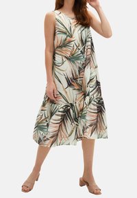 Robe maxi florale en tissu léger, avec des imprimés de feuilles de palmier verts et pêche, sans manches et avec un ourlet en volants.