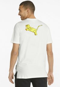 Tricou alb cu un grafic pixelat de câine galben pe spate. Material din bumbac; manșon scurt; slit lateral pentru confort.