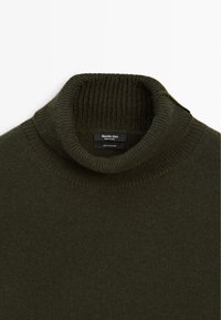 Maglione turtleneck in cashmere a coste di colore verde scuro, con colletto ripiegato e etichetta del marchio visibile all'interno del collo.