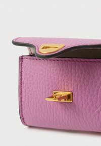 Portofel roz din piele texturată, cu o închizătoare metalică aurie și margini contrastante închise la culoare. Prezintă o curbură ușoară la deschidere, cu cusături vizibile.