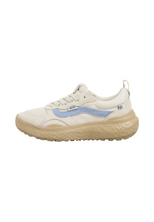Zapatilla beige con una franja lateral azul claro, parte superior de malla y ante, suela gruesa y texturizada, con cordones y un pequeño lazo en el talón.