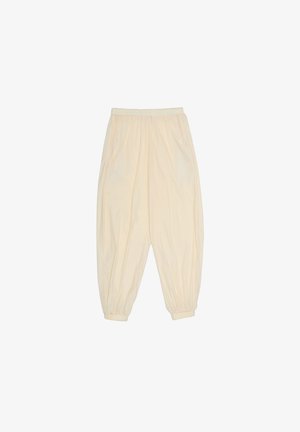 Luźne spodnie w kremowym kolorze, z elastycznym paskiem w talii i mankietami, z kieszeniami po bokach, wykonane z lekkiego materiału.