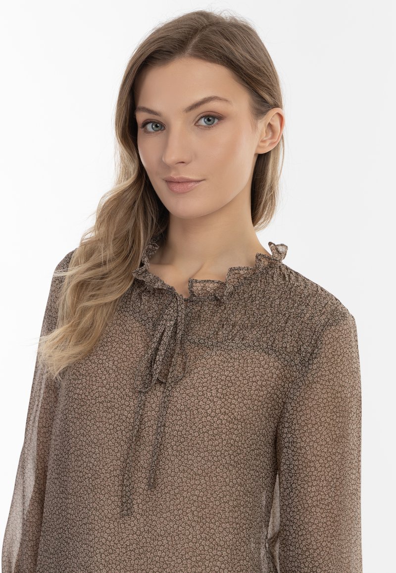 Durchsichtige braune Bluse mit kleinen Blumenmustern, gerafftem Ausschnitt und einer Bindeschließe. Sie ist mit langen Ärmeln und einem lockeren Schnitt entworfen.