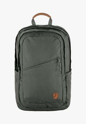 Mochila de tela verde con un asa de cuero marrón, múltiples compartimentos con cremallera, bolsillos laterales y un parche con un logotipo que presenta un zorro estilizado.