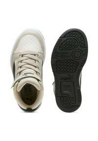 Sneaker Puma crema e nera mostrata vista dall'alto e dal suola, con lacci, punta perforata e suola in gomma nera testurizzata.