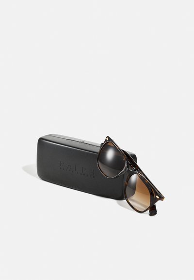Brown tortoiseshell sunglasses with gradient lenses resting on a black case embossed with "RALPH." Case features a sleek rectangular shape.
