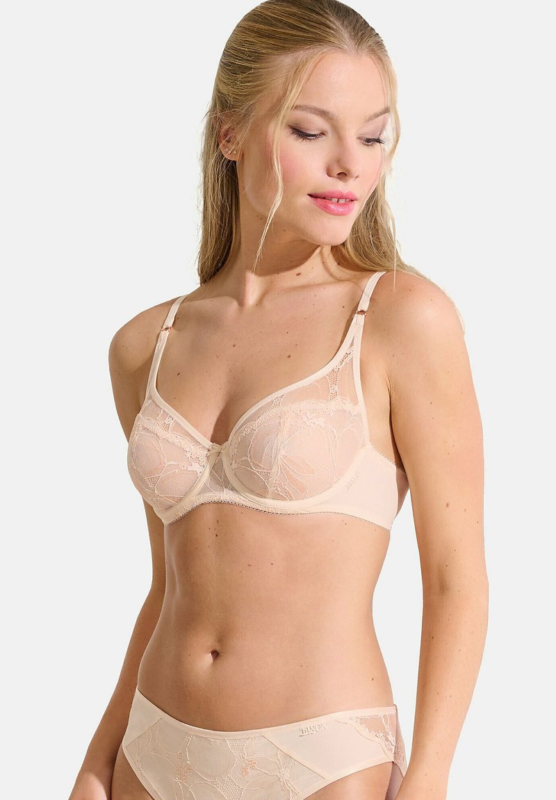 Soutien-gorge beige avec armatures, recouvert de dentelle florale, avec des bretelles réglables et un petit nœud au centre. Tissu doux et design sans coutures.